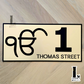 Ek Onkar house number sign in gold acrylic mounted beside modern home entrance.