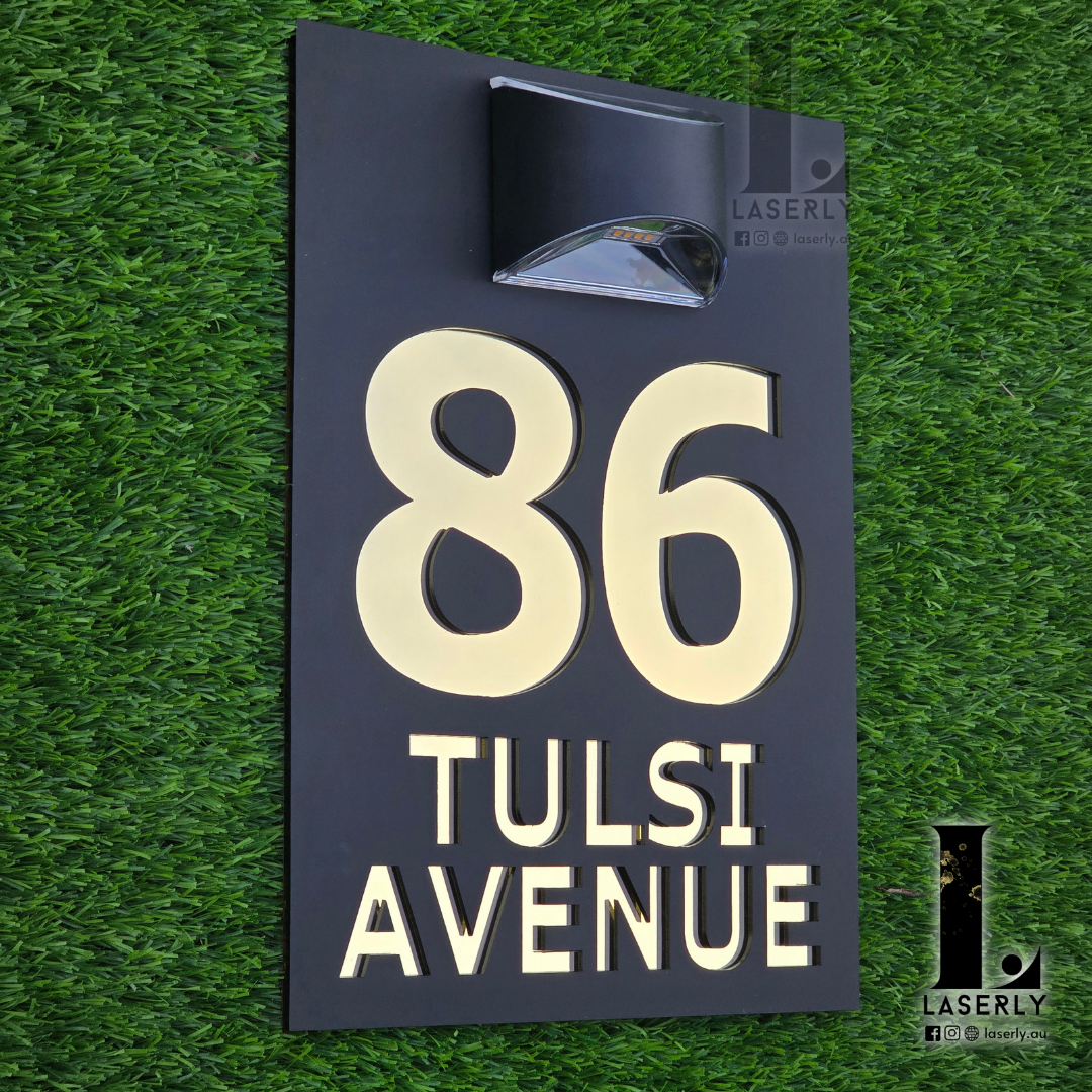 Black acrylic address plaque with solar powered LED light installed on exterior wall.