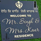 Modern Punjabi-style house number plaque on a home exterior wall.