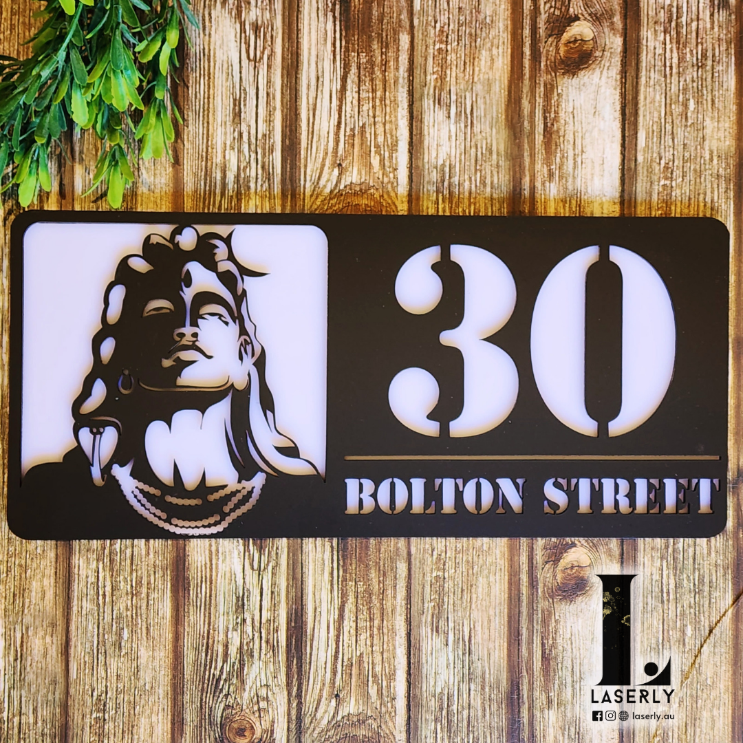 Adiyogi Shiva-themed house number sign mounted on a modern exterior wall.