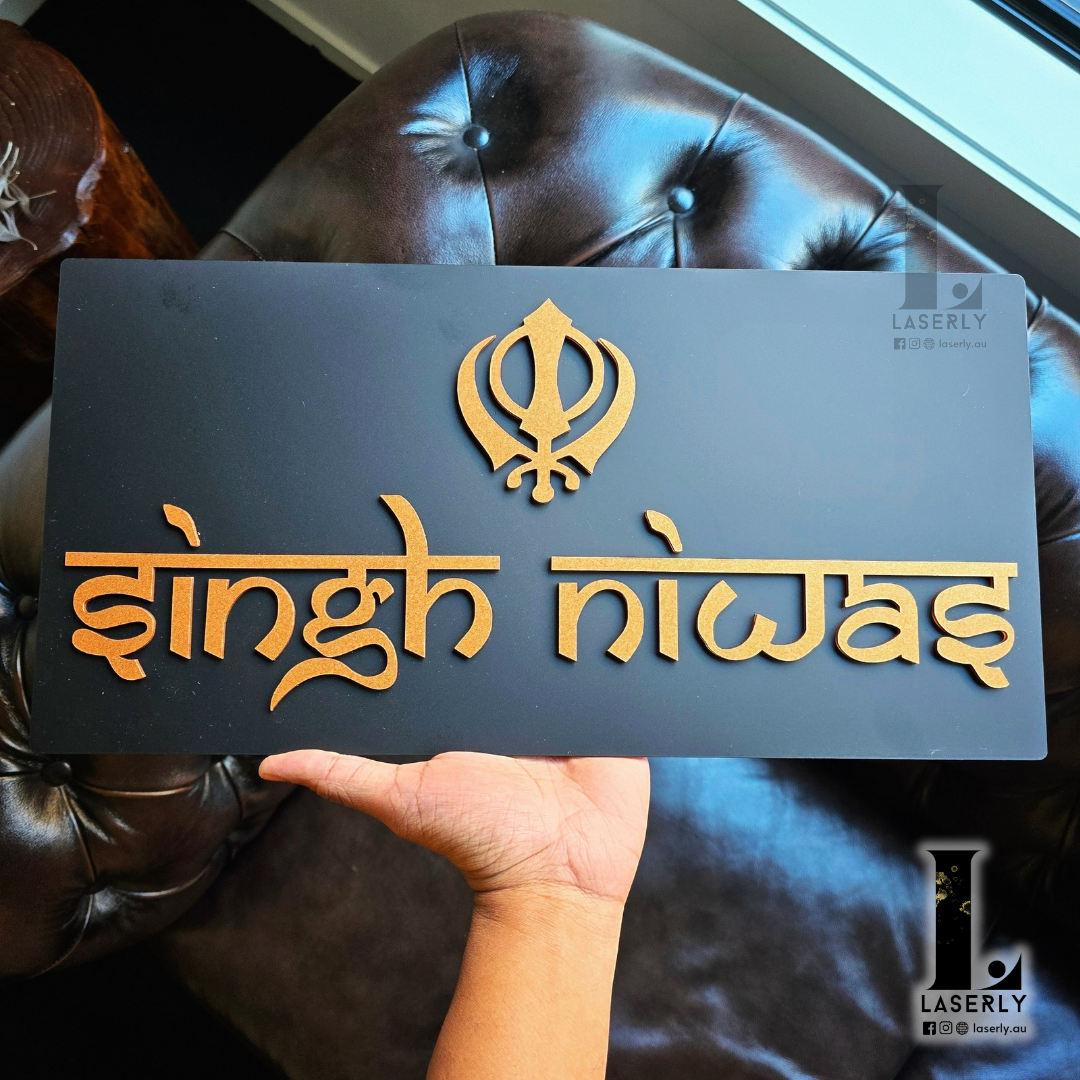 Close-up of black and bronze Om and Ek-Onkar house number sign for home exterior.