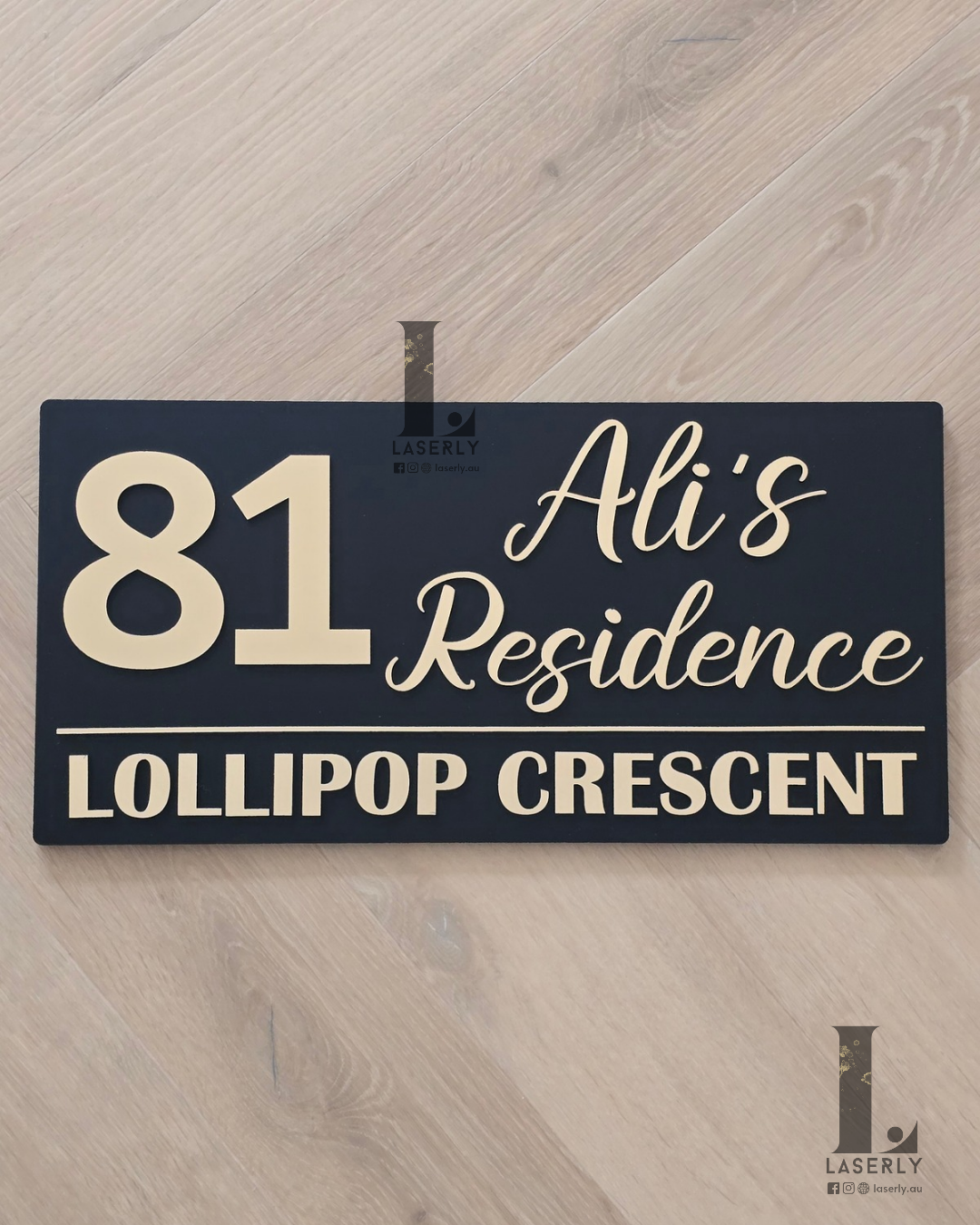 Black and brushed gold house name sign mounted on exterior wall beside front entrance.