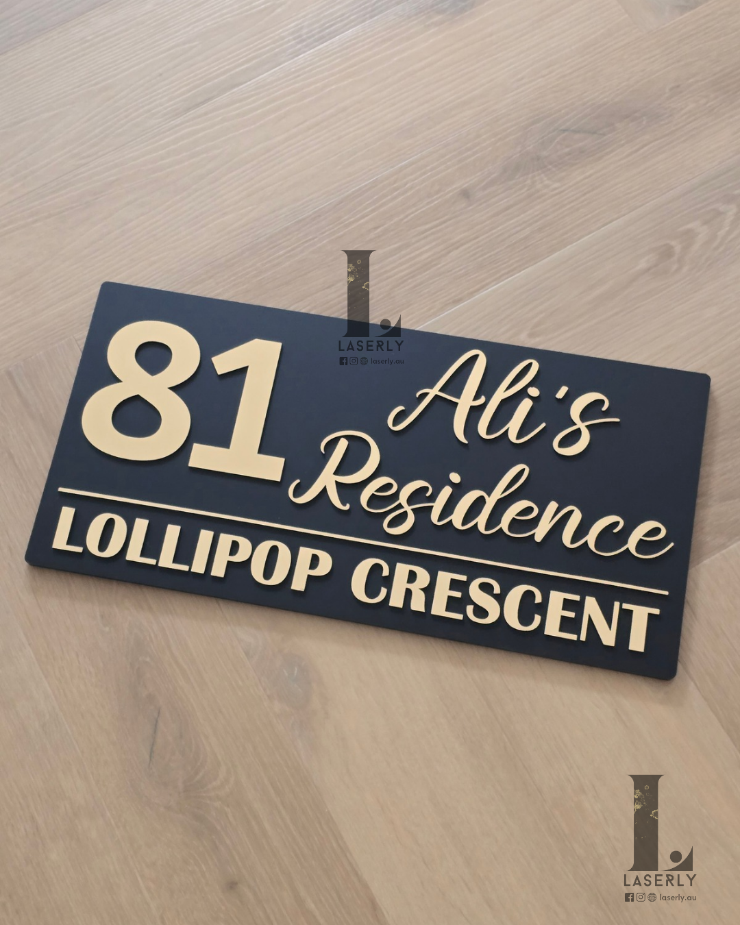 Modern acrylic house name plaque in black with brushed gold lettering on home façade.