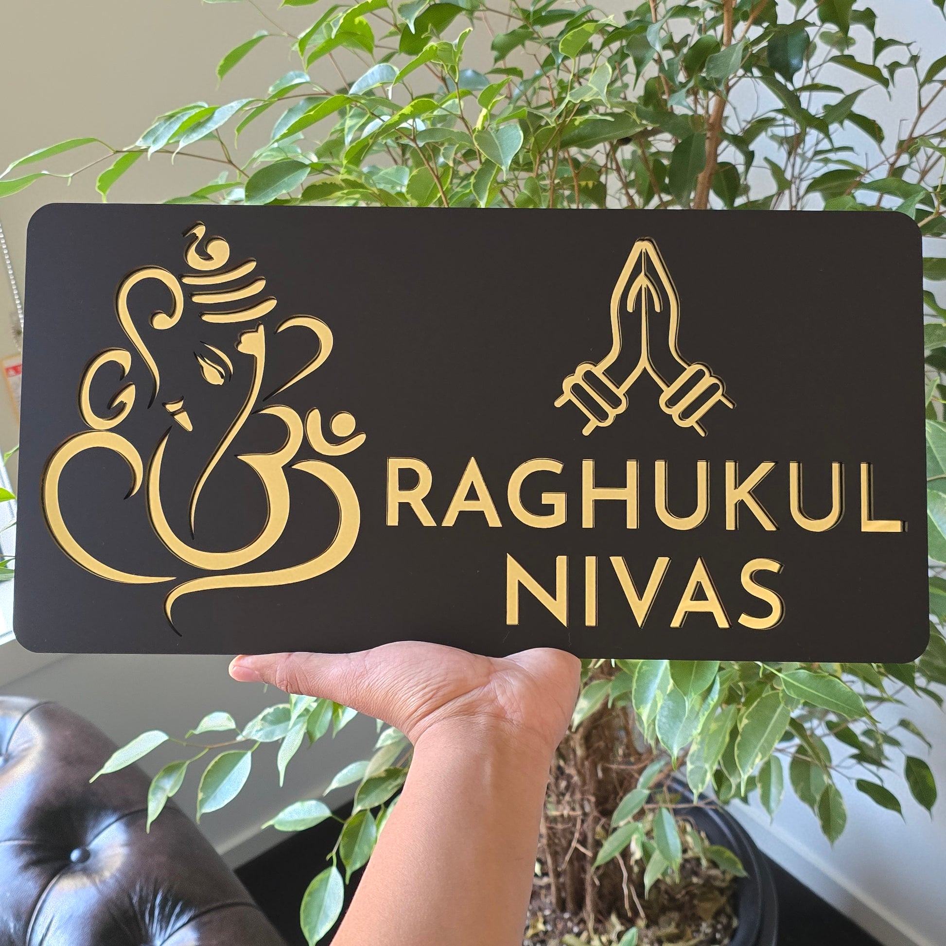 Black and mirror gold Ganesha Namaste house number sign mounted on a modern exterior wall.