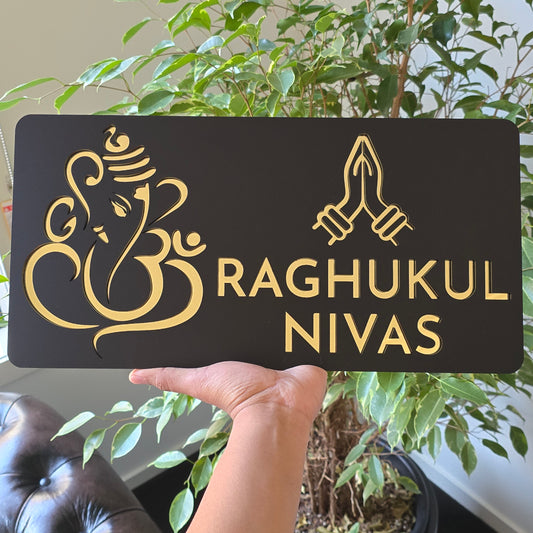 Black and mirror gold Ganesha Namaste house number sign mounted on a modern exterior wall.