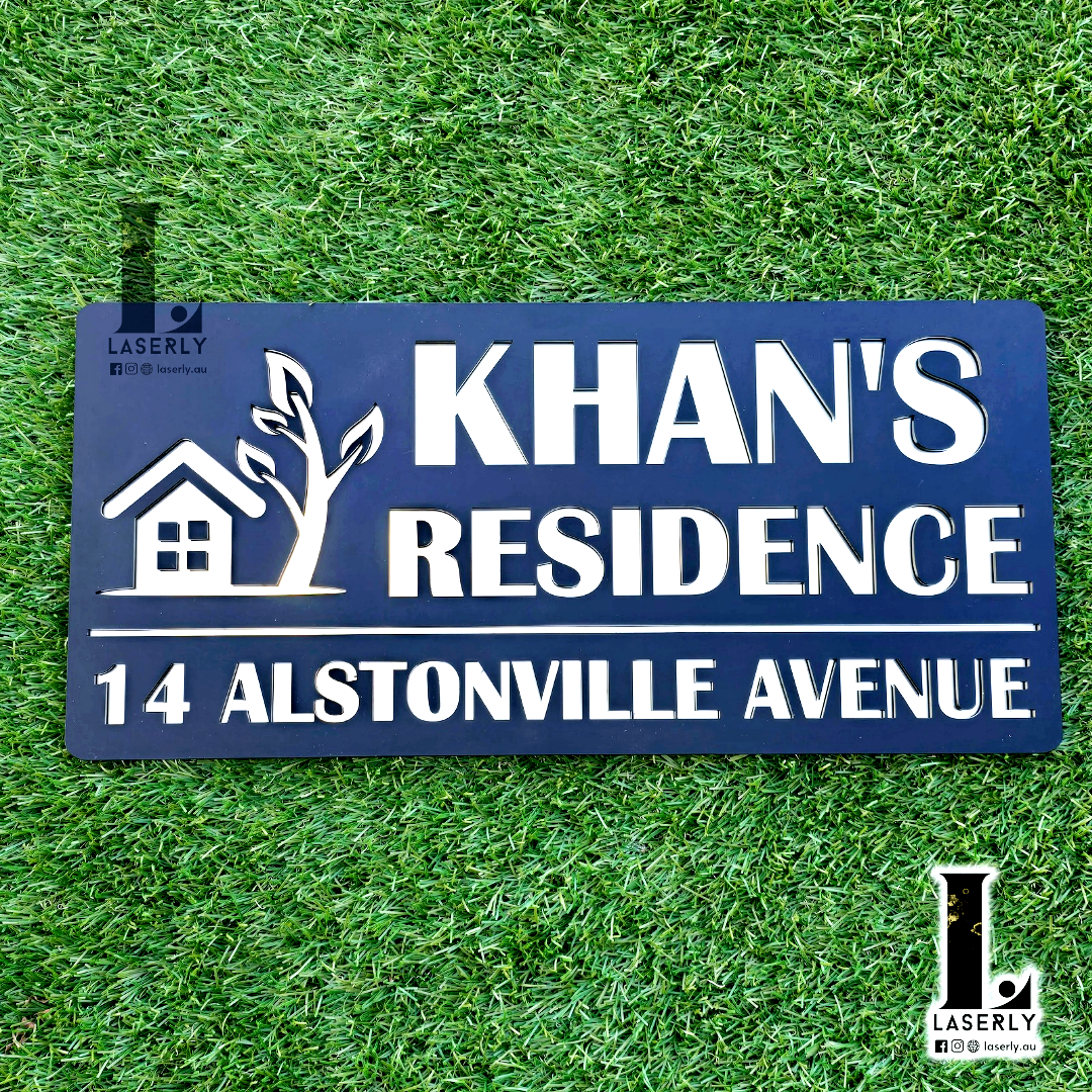 Black and mirror gold acrylic house name sign mounted beside a modern front door.