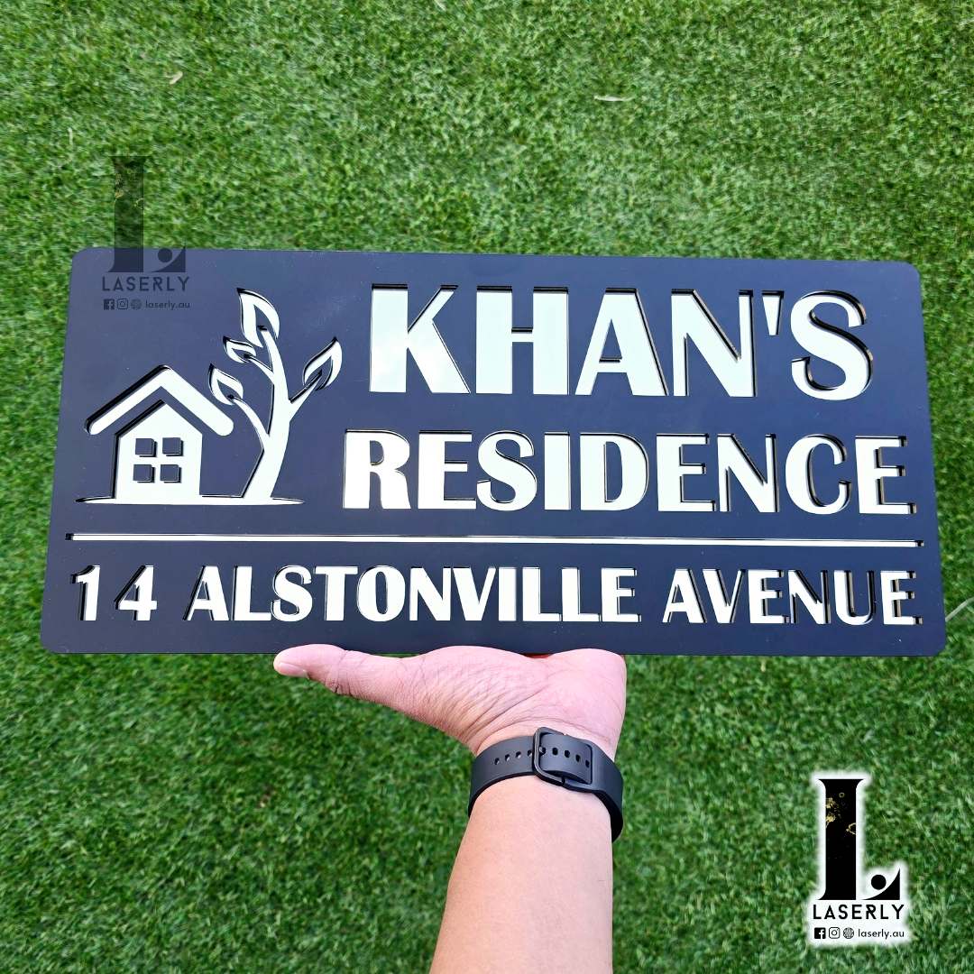 Custom house name plaque in matte black and mirror gold acrylic installed on exterior wall.