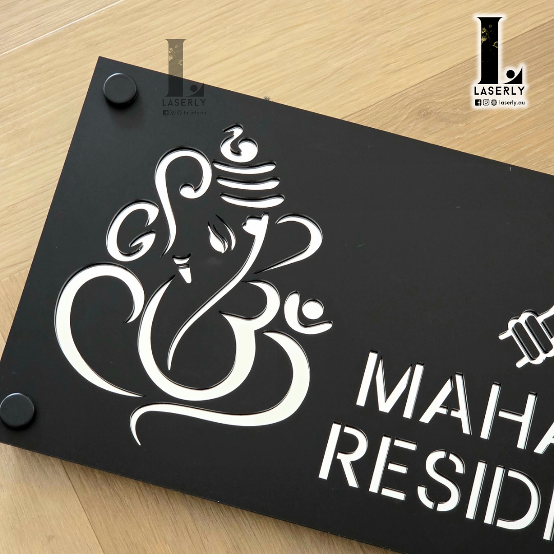 Stylish black and mirror silver Ganesha house number sign fixed to rendered exterior wall.