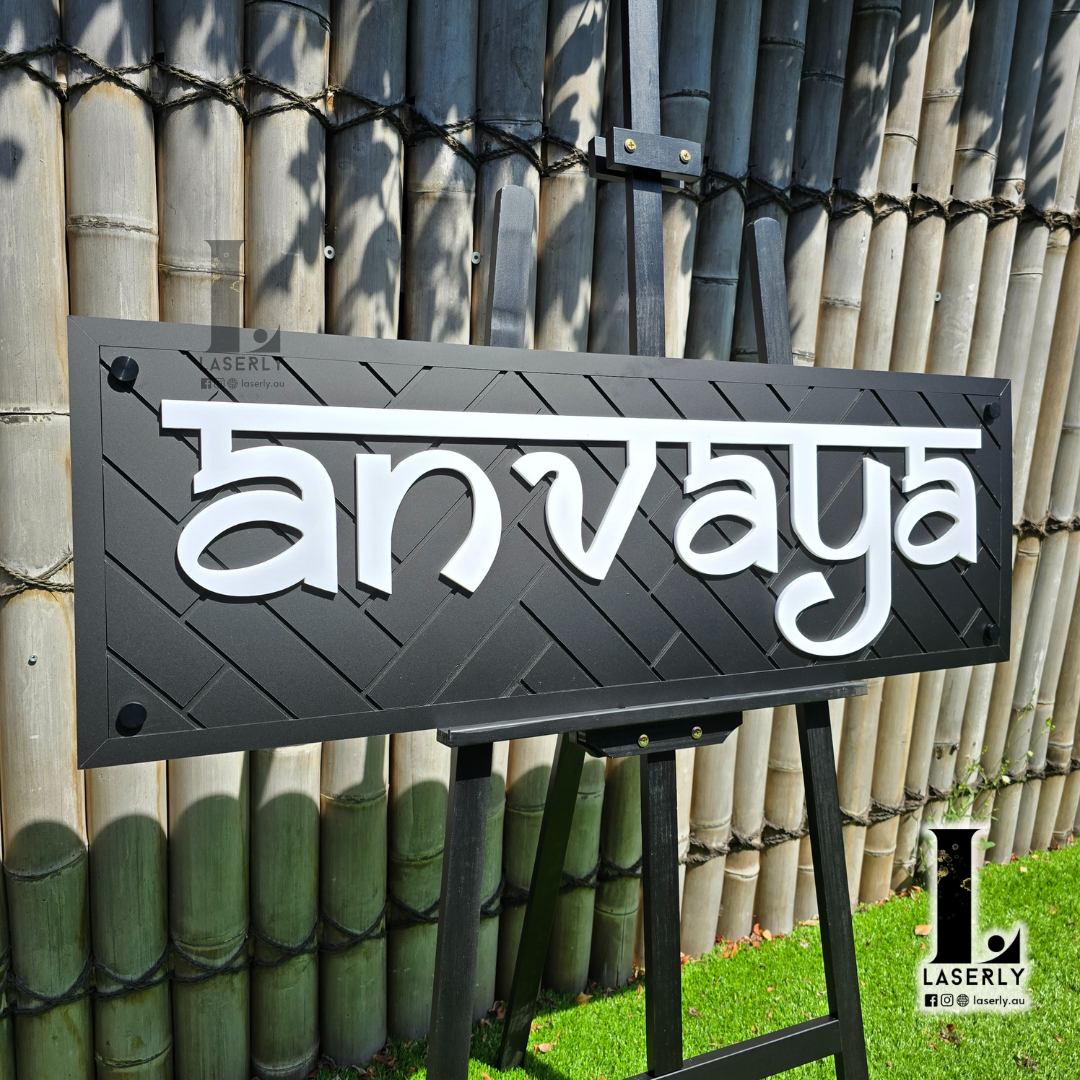 Black pattern house name sign mounted beside front door with decorative laser-cut detailing.