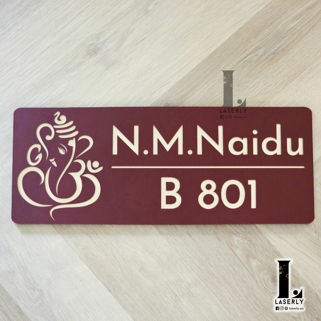 Brown and gold Ganesha house number sign mounted beside a modern front door.