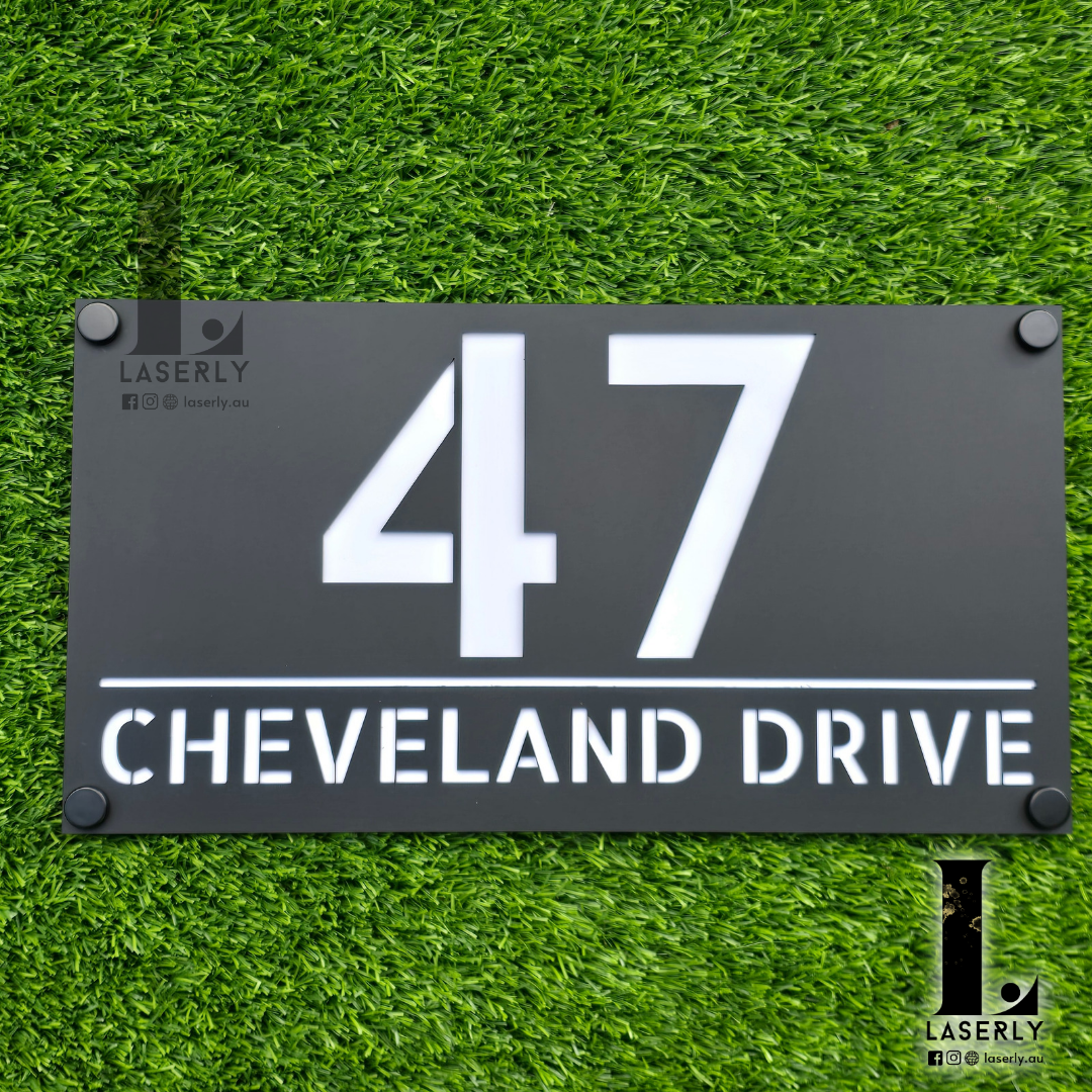 Modern acrylic house number sign mounted beside a front door on an exterior wall.