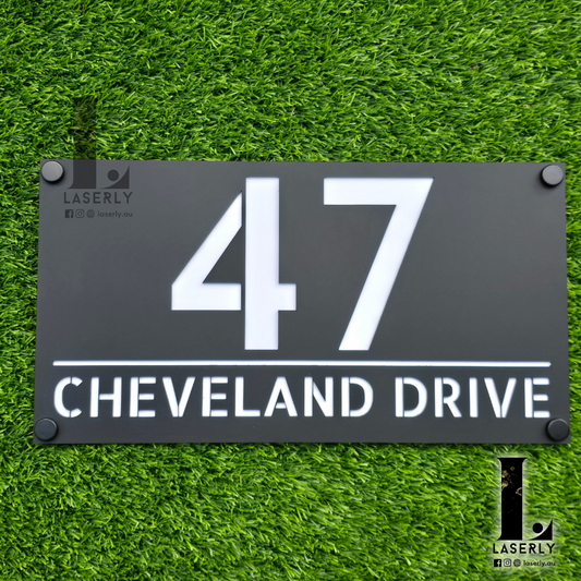Modern acrylic house number sign mounted beside a front door on an exterior wall.