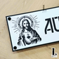 Contemporary Jesus house name plate fixed on rendered exterior wall.