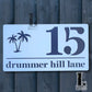 Modern acrylic house number sign featuring a palm tree design, mounted beside a front door.
