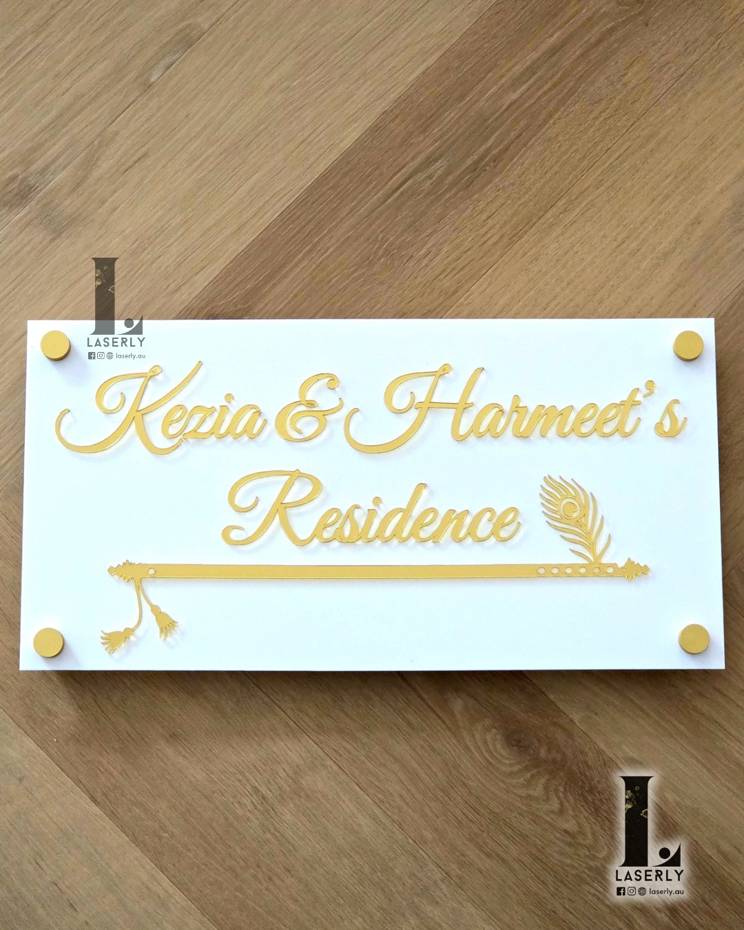 Modern flute-shaped house name sign in white with mirror gold accents mounted on exterior wall.