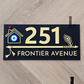 Black flute-themed house number sign featuring a protective evil eye design mounted on exterior wall.
