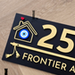 Decorative black exterior house number sign with flute artwork and evil eye protection symbol.