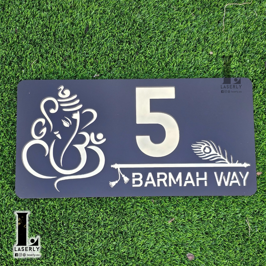 Ganesha and Krishna flute-themed house number sign mounted on modern exterior wall.
