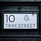 Modern minimalistic house number sign featuring Lord Ganesha design, mounted on exterior wall.