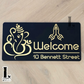 Ganesha Namaste house number sign featuring folded hands design with laser-cut acrylic finish mounted beside front door.
