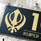 Black and metallic gold Kandha house number plaque displayed beside front door.