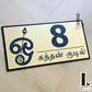 Contemporary Murugan-inspired Tamil Om house number plaque displayed on an exterior home wall.