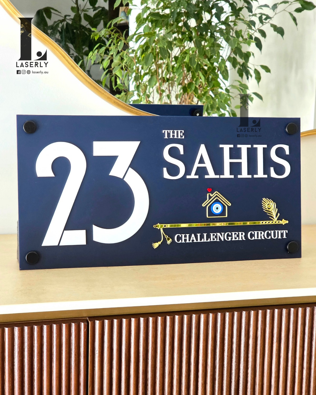 Modern navy blue evil eye house number sign with decorative flute detailing mounted on exterior wall.