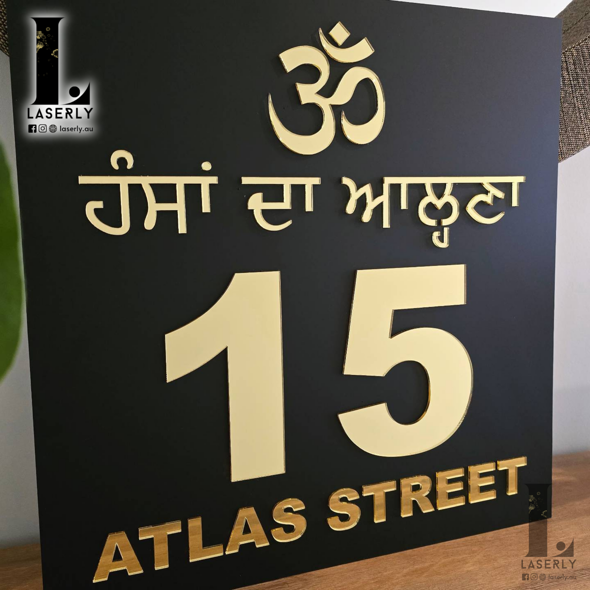 Elegant gold and black OM house number sign enhancing home entrance.