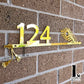 Modern house number sign featuring Lord Krishna’s flute design mounted beside the front door.