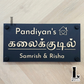 Tamil house number sign in elegant Tamil script mounted beside the front door on an exterior wall.