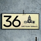 Modern Thirumala house number sign mounted on a sleek exterior wall.