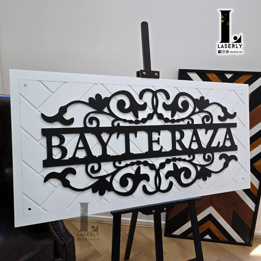 Elegant white patterned home name sign mounted on exterior wall beside front door.